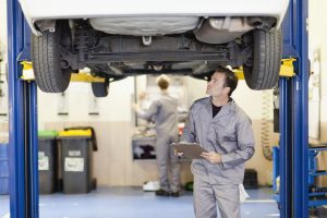 Tecchnician inspecting underside of vehicle in MOT centre